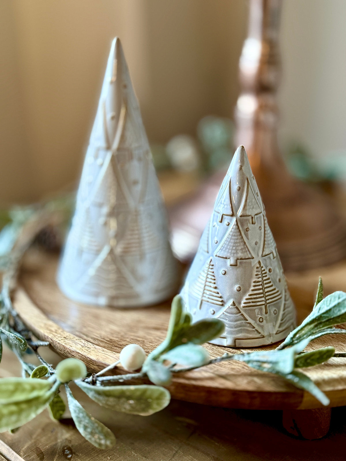 Wooden styling board with festive garland and neutral ceramic tree decorations